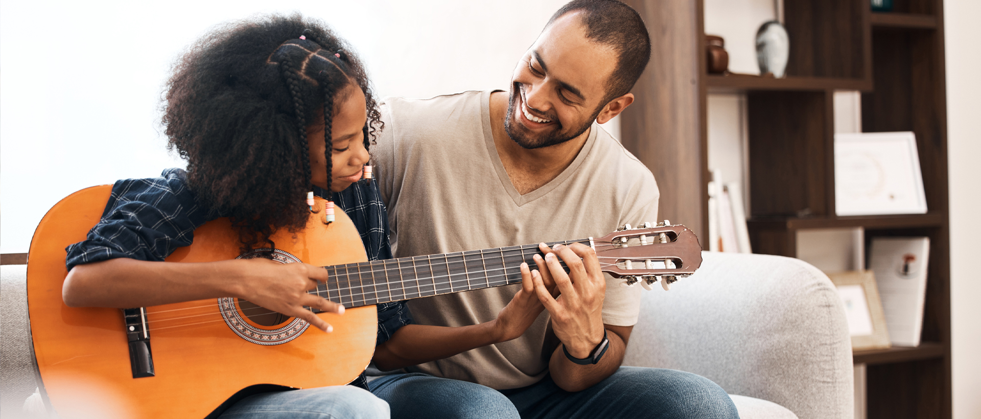 Image of father with daughter playing guitar.