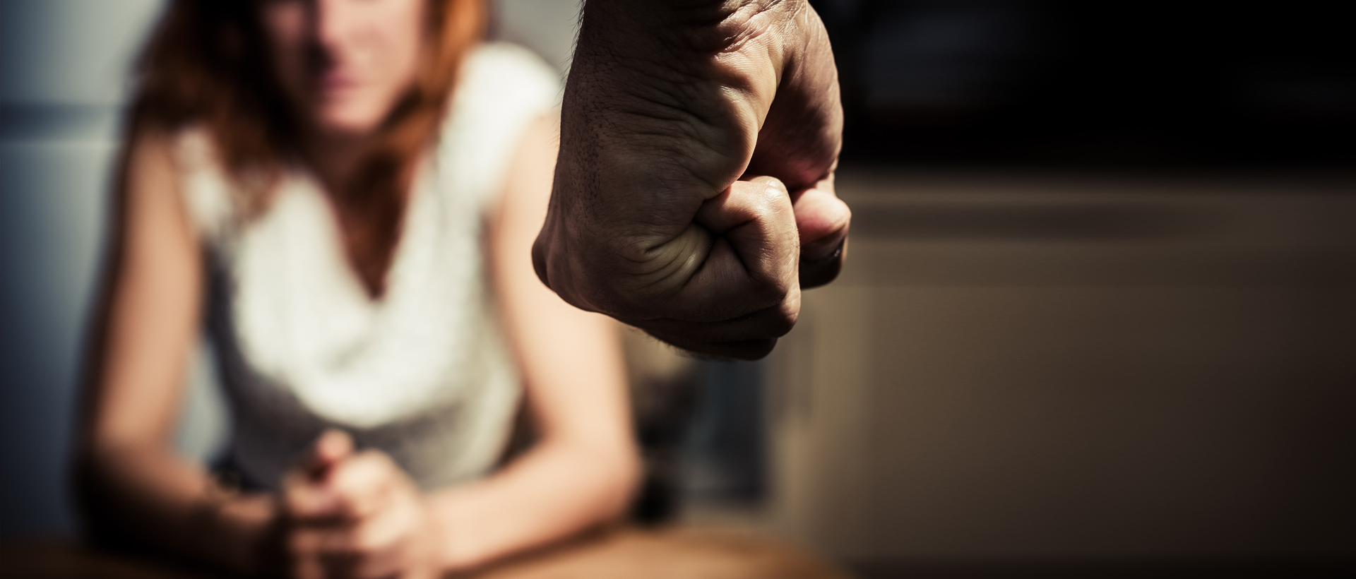 Woman sitting in background with image of a man's fist in front of her.