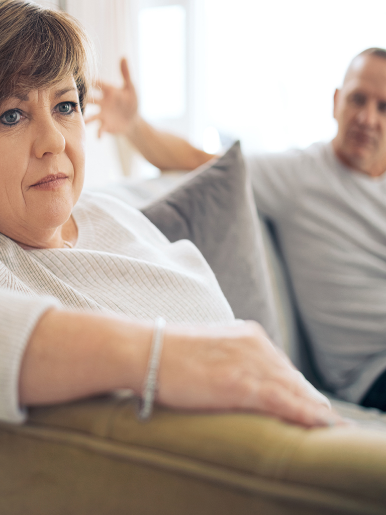 Woman and man sitting on couch arguing.