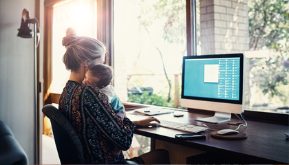 woman holding baby while working at desk