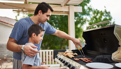 Man cooking with son on grill.