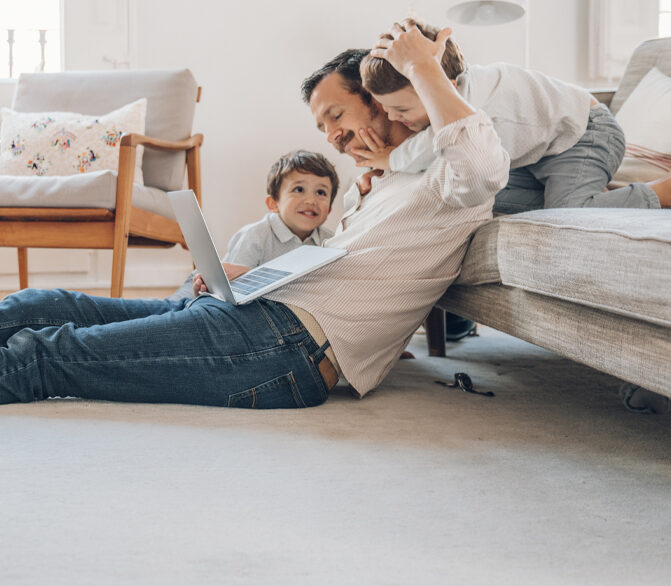 Image of father with children playing on family room floor.