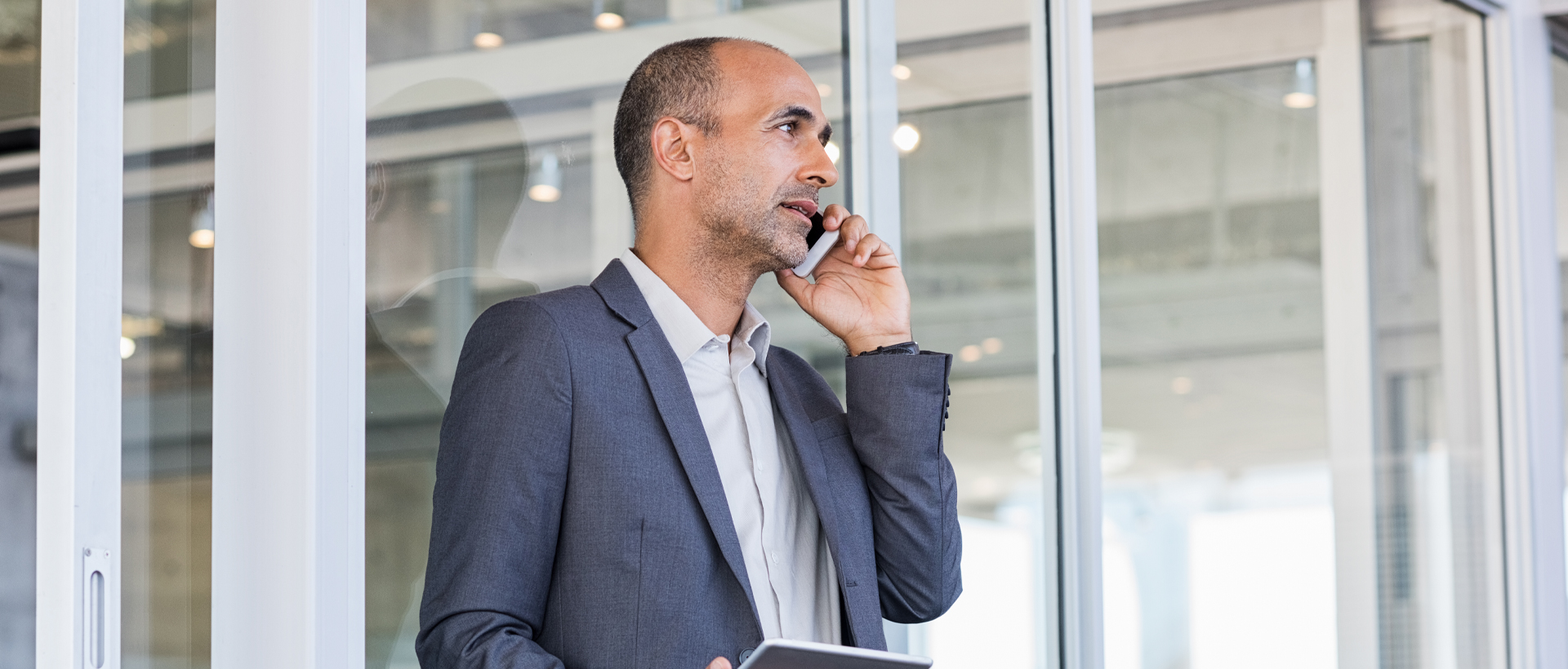 Business man on phone looking out window while on cell phone.