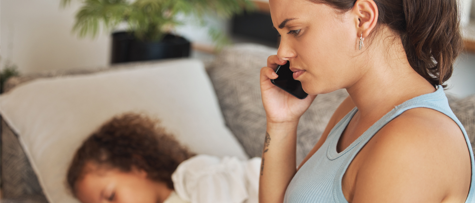 Concerned woman on phone with sleeping child near.