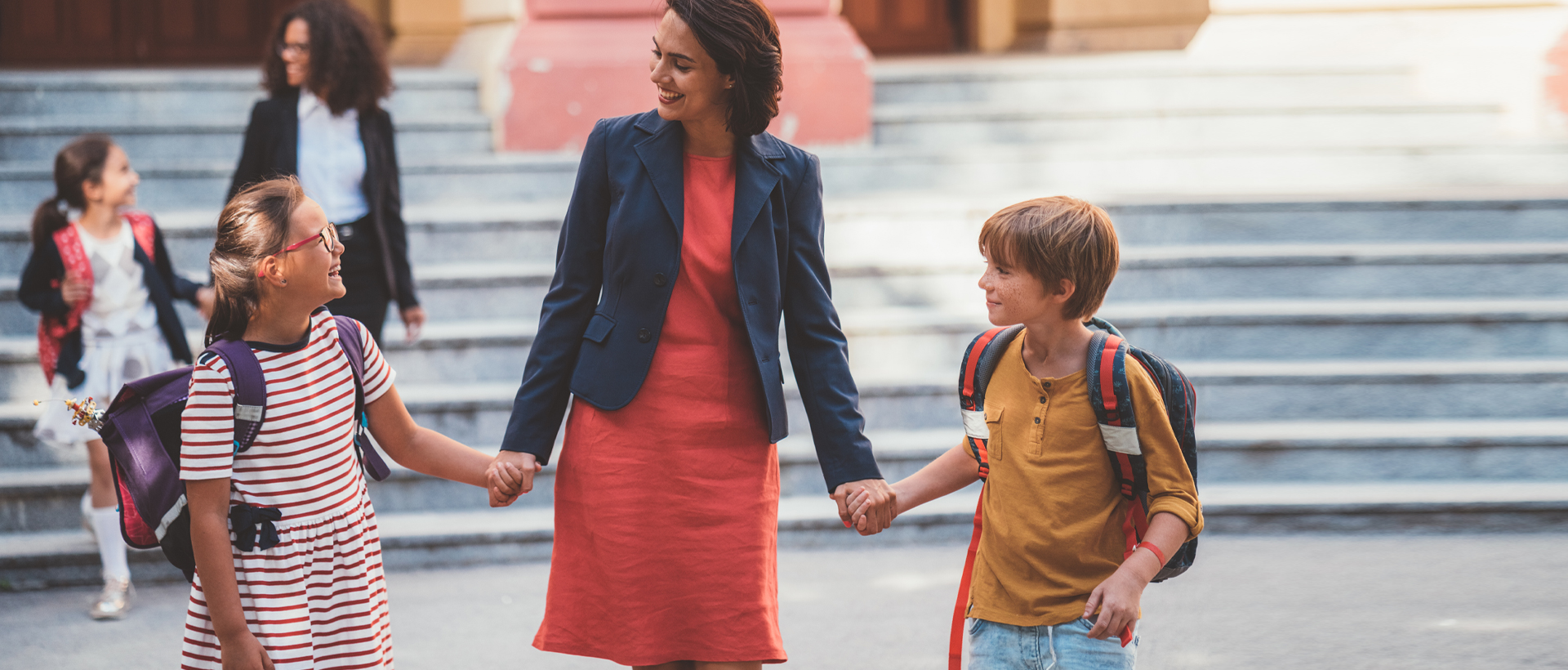 Mother and two young children standing outside of school.