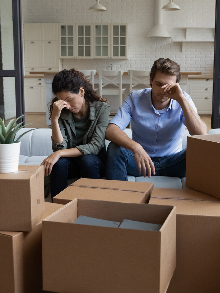 Couple sitting behind stack of boxes.