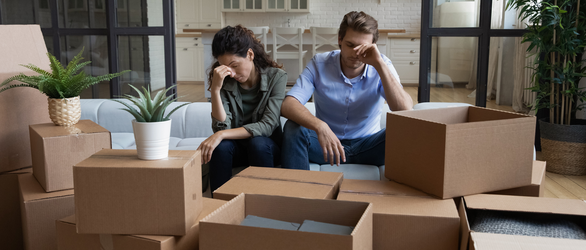 Concerned man and woman sitting in room surrounded by boxes.