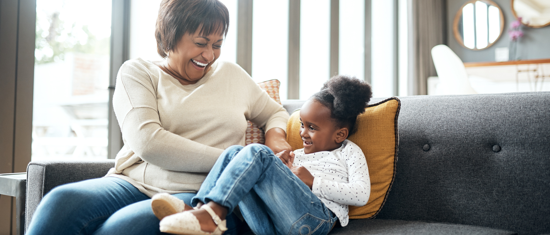 Grandmother playing with granddaughter on couch.