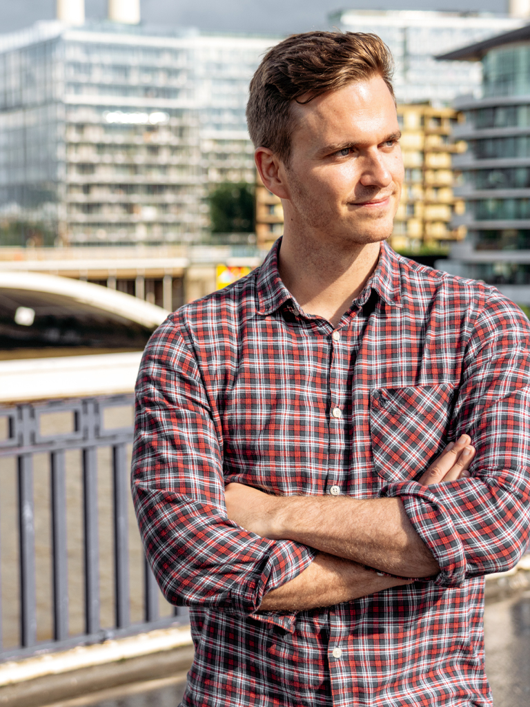 Man standing on bridge with arms crossed.