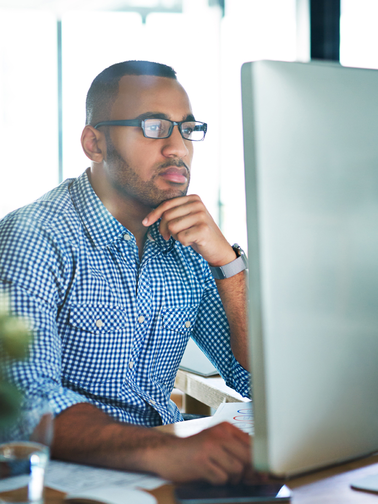 Man working at computer looking at computer monitor.