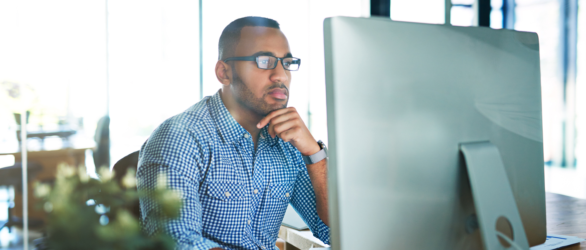 Man sitting at desk looking at computer monitor.