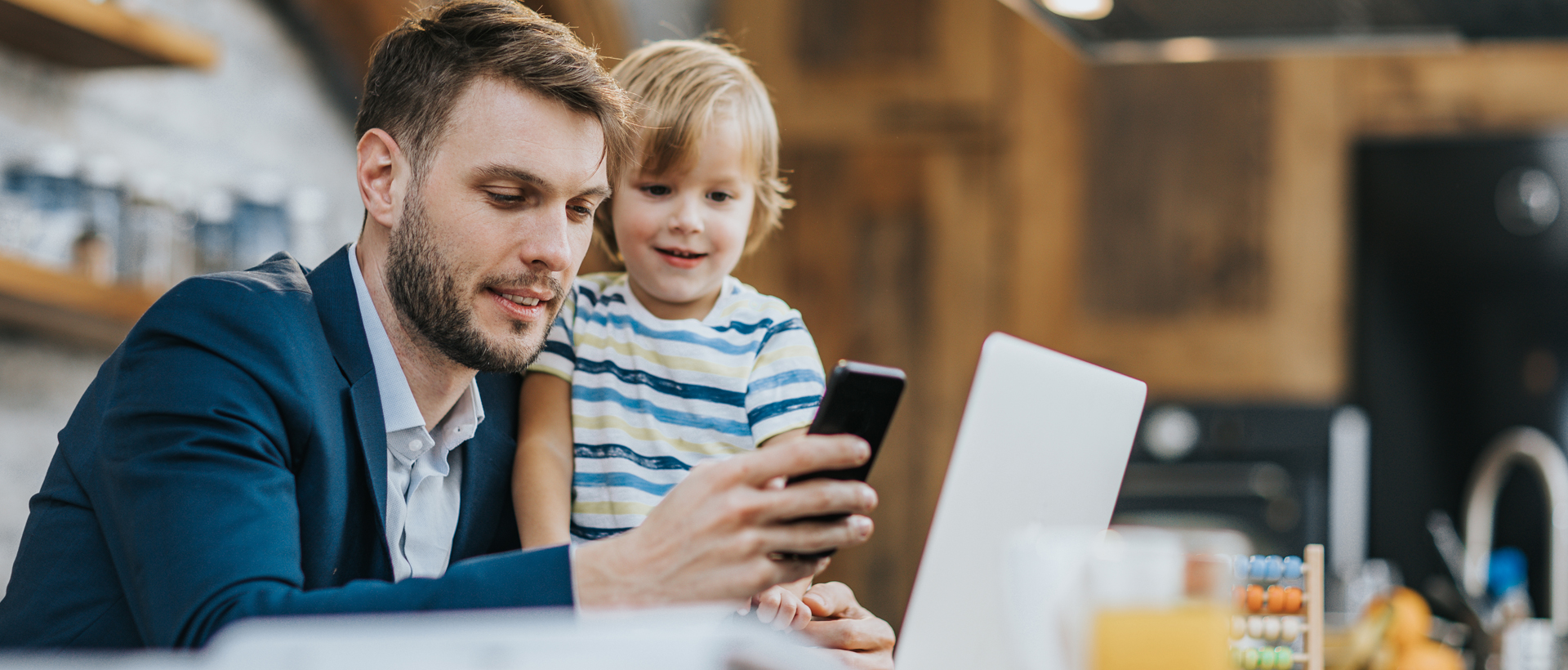 Father and young son look at mobile phone.