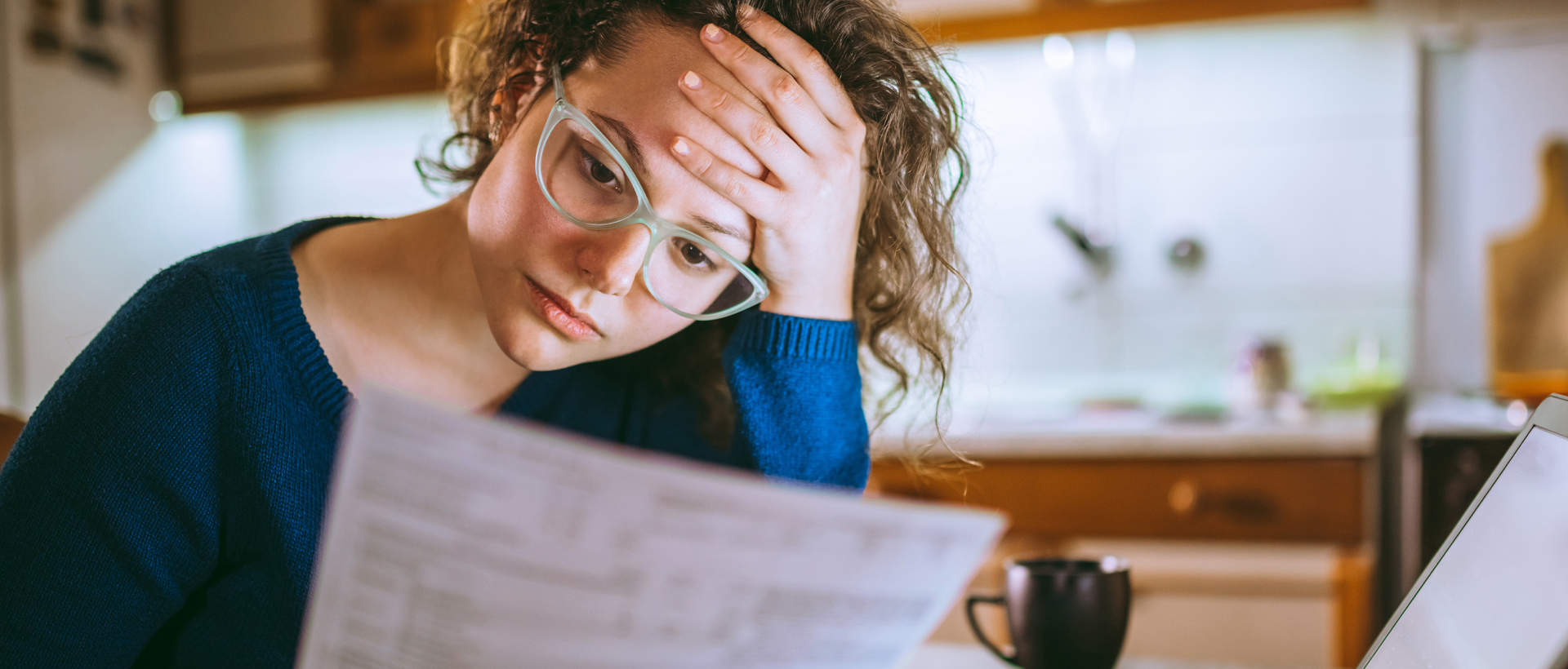 Concerned woman reviewing documents at kitchen table.