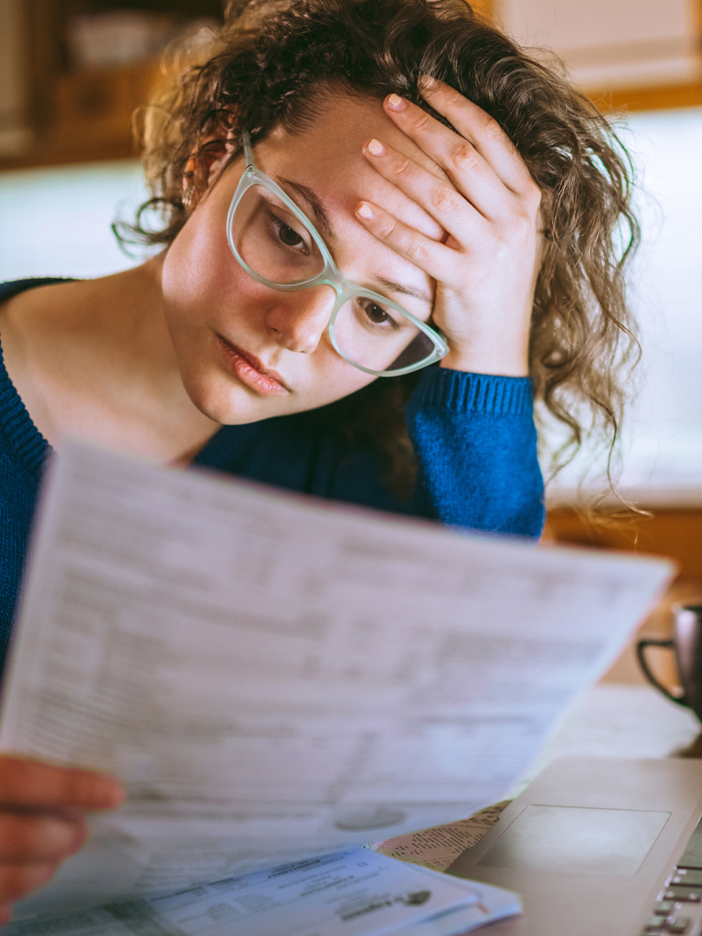 Concerned woman reviewing documents at kitchen table.